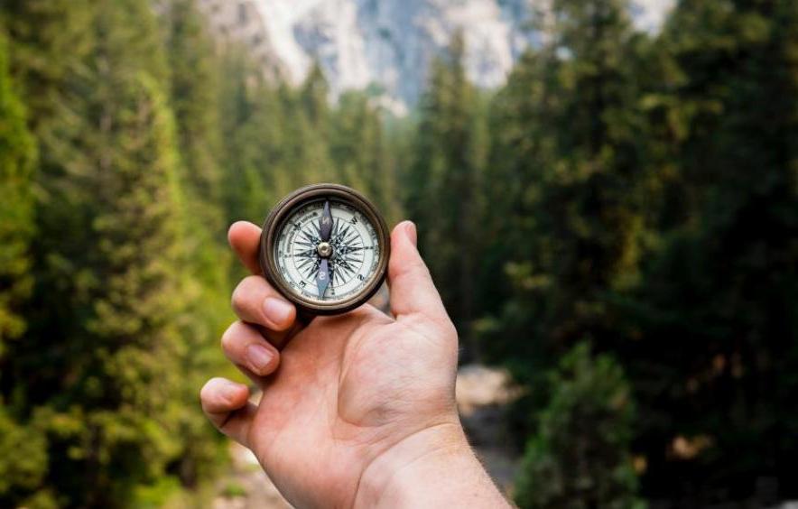 compass with hand and mountains